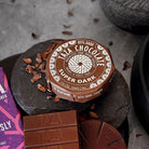 Taza Chocolates Super Dark chocolate bars on a stone surface with cocoa nibs.