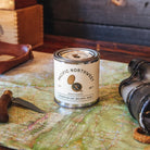 Candle labeled 'Pacific Northwest' on a map with binoculars and knife in vintage setting