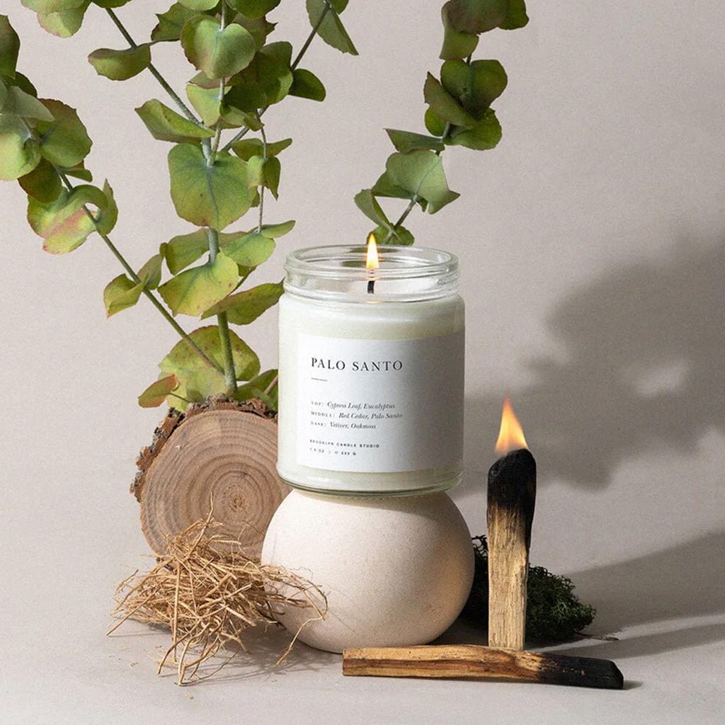 Palo Santo candle with eucalyptus leaves and a wooden match on a neutral background