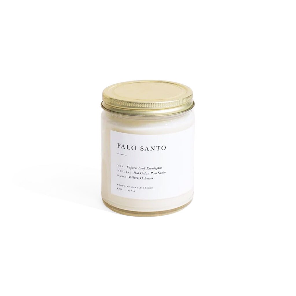 Candle jar labeled 'Palo Santo' with a gold lid on a white background