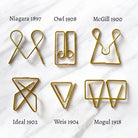 Six gold-colored metal wire paperclips arranged in a 2x3 grid on a white marble background, each labeled with its name and year: Niagara 1897, Owl 1908, McGill 1900, Ideal 1902, Weis 1904, and Mogul 1918.