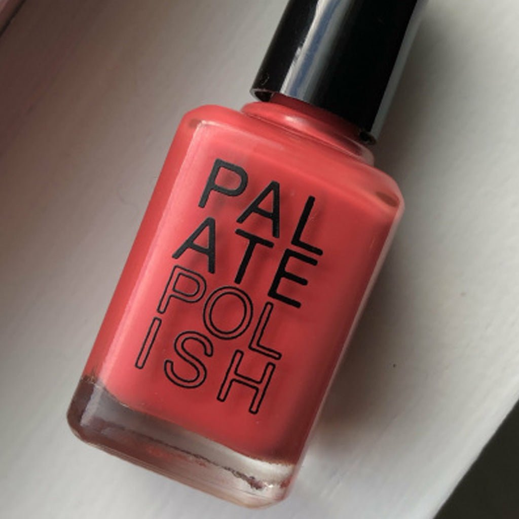 Bottle of pinkish-orange Paprika nail polish on light surface