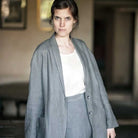 Woman wearing merchant and mills sewn jacket and trousers against light background