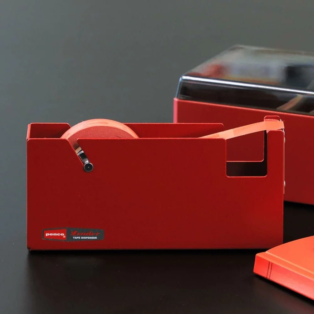Large red steel tape dispenser on a dark surface with a gray background