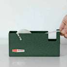 Green tape dispenser with a hand pulling out tape on a white background