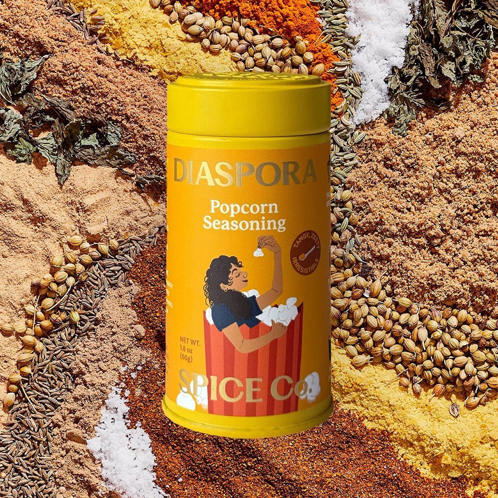 Diaspora Popcorn Seasoning canister surrounded by various spices.