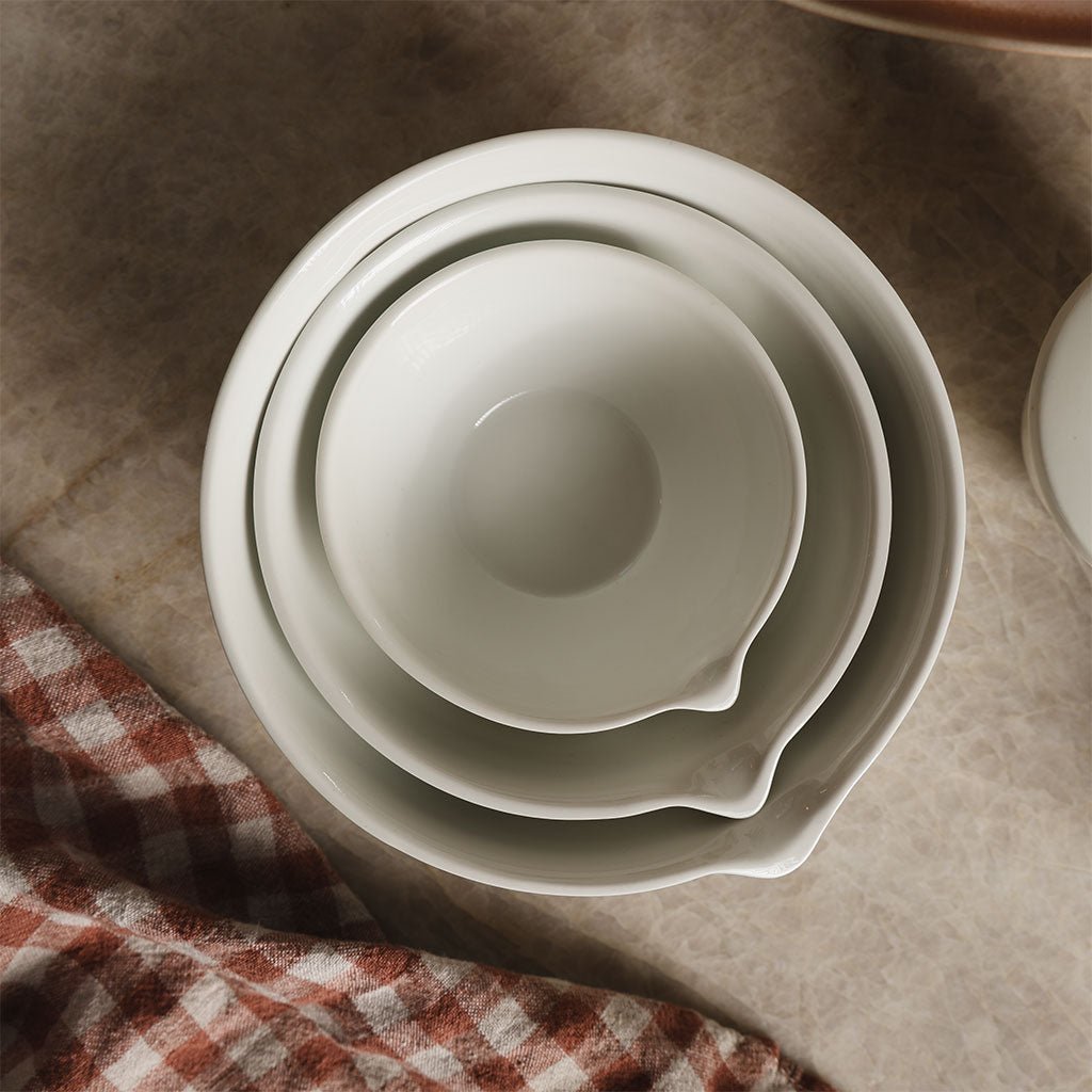 Three nesting white porcelain bowls on kitchen counter. 