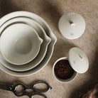 White porcelain bowls and jar filled with spices on kitchen counter. 