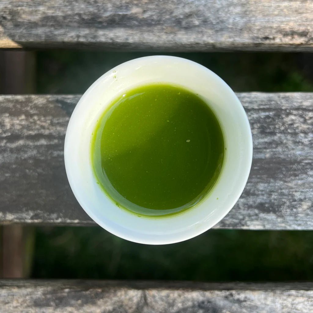 Sencha green tea in white cup against wooden surface