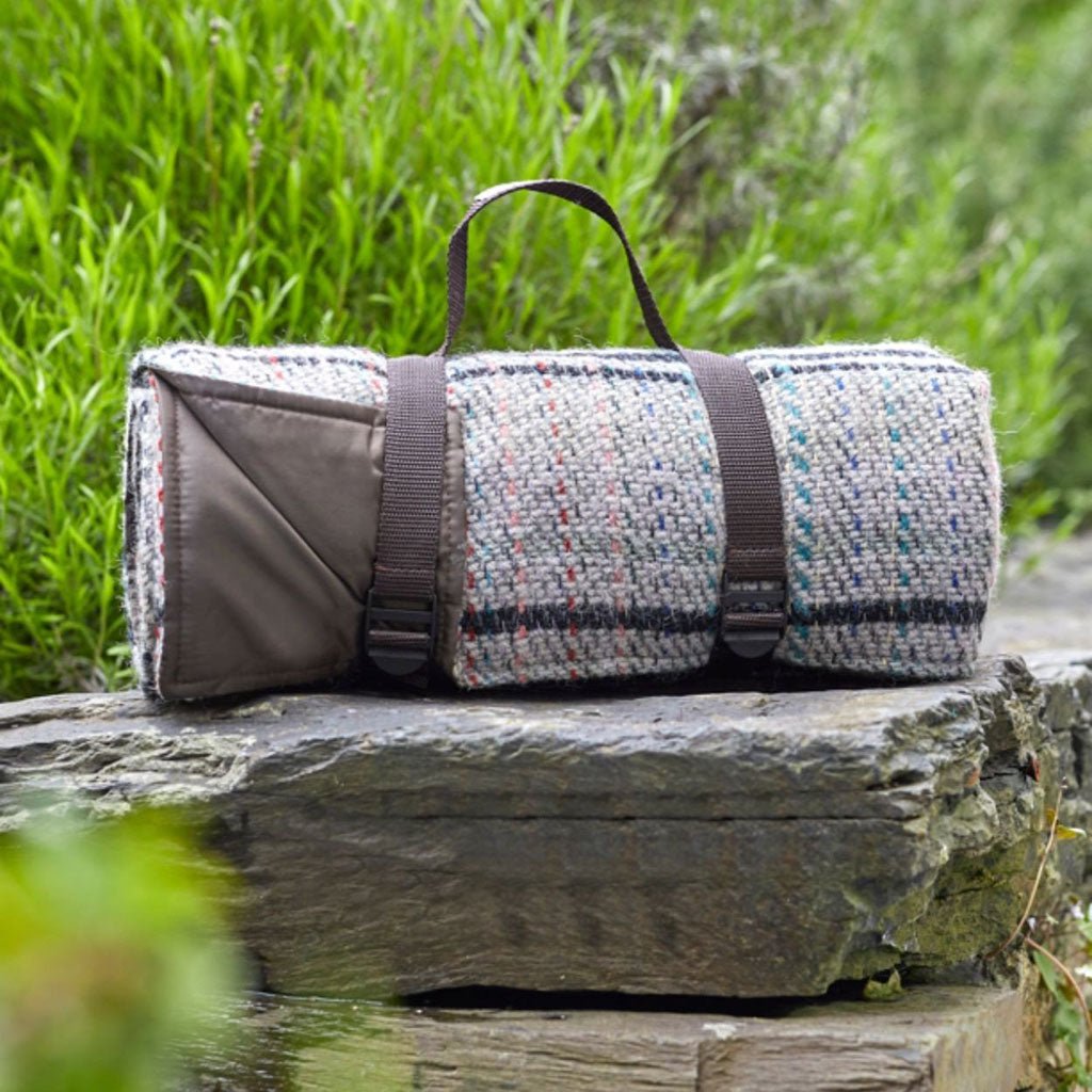 A rolled picnic blanket with straps for carrying.