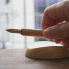 Hand holding a pen over a wooden pen rest with a blurred background