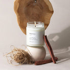 Candle in a jar labeled 'Santal' with wooden elements on a neutral background