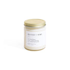 Candle jar labeled 'Sea Salt + Surf' with a gold lid on a white background