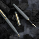 Two pens with gold accents on a dark, textured surface