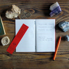Lined notebook with writing on table next to rocks and shells