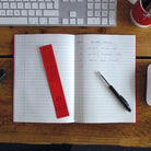 Open lined notebook with pen and writing on wooden background