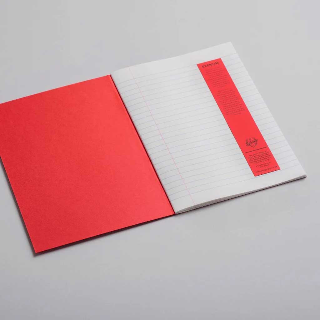 Open exercise lined notebook with red cover on light background