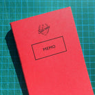 Close up of red memo notebook on gridded background