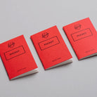 Three red pocket notebooks on light background