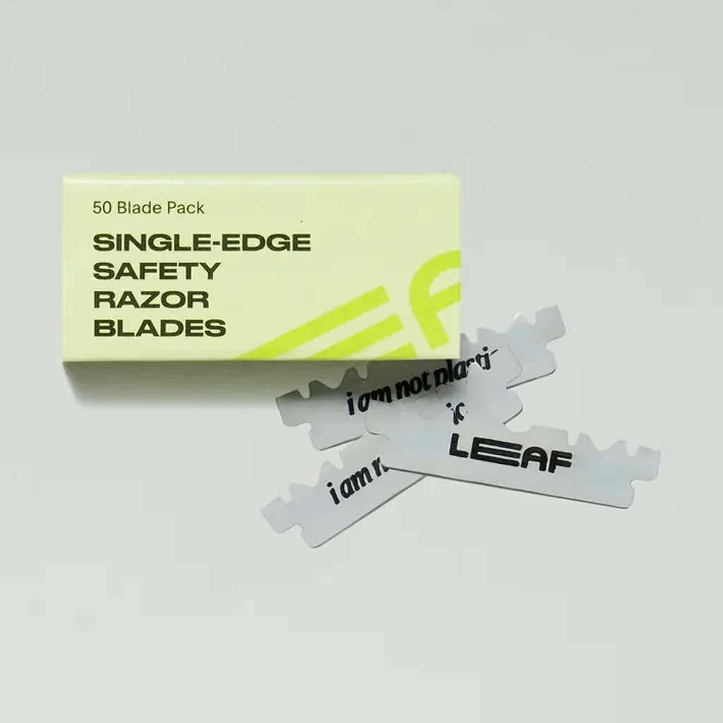 Box of single-edge safety razor blades with blades displayed on a gray background