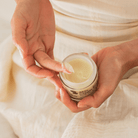 Person holding a jar of cream with a soft focus background