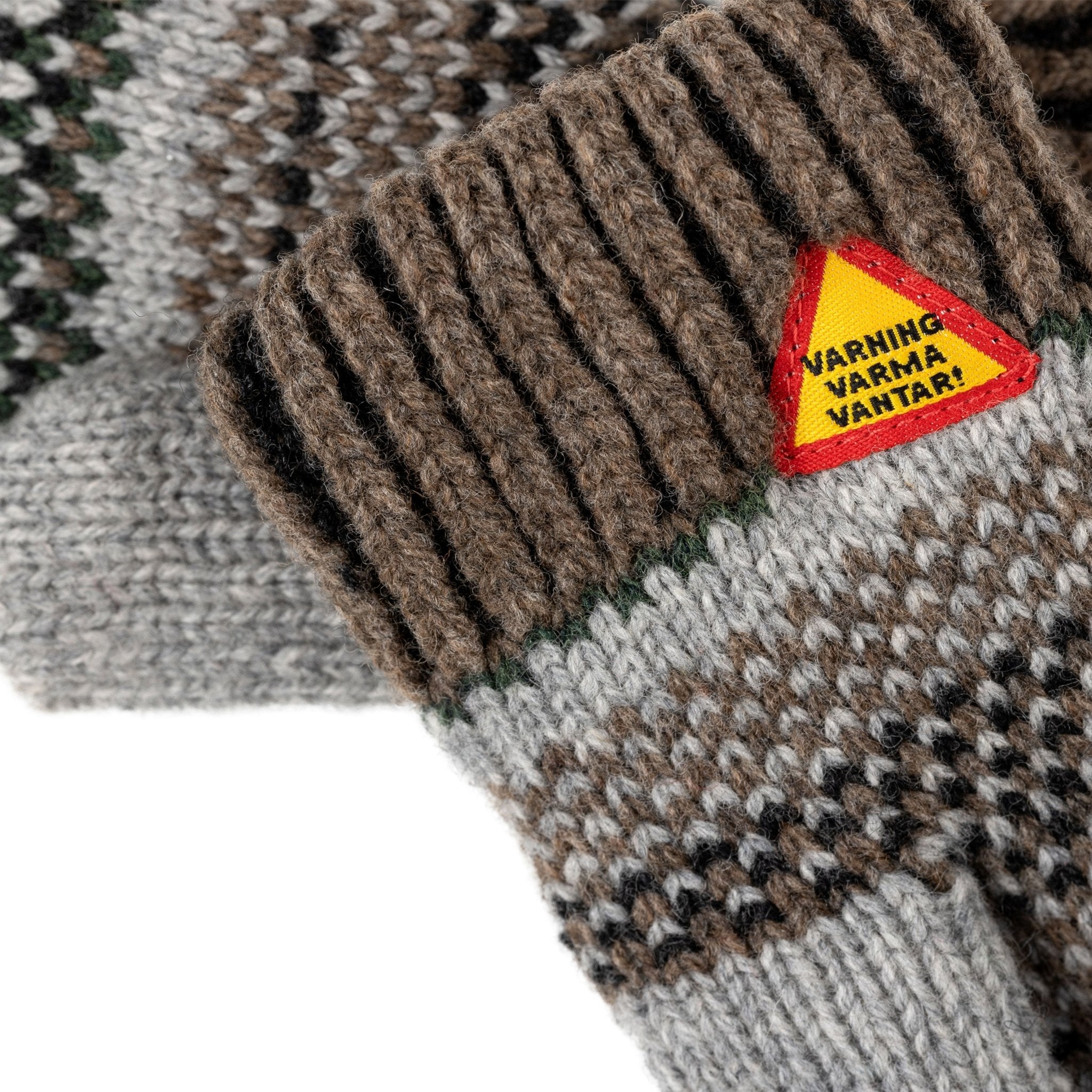Knitted mittens with a triangular warning label on a patterned background