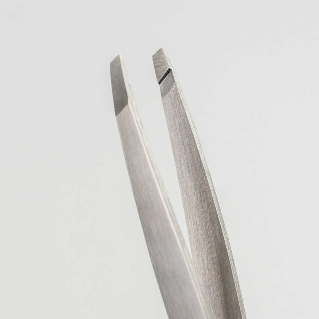 Pair of silver tweezers on a light gray background