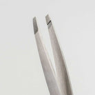 Pair of silver tweezers on a light gray background