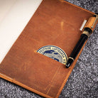 Brown leather notebook with Lufthansa logo and a pen on a textured surface