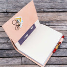 Open notebook with natural undyed leather notebook cover with a pen on a wooden surface