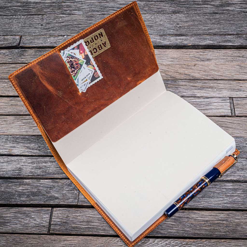 Open leather notebook cover with a pen on a wooden surface