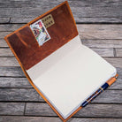 Open leather notebook cover with a pen on a wooden surface