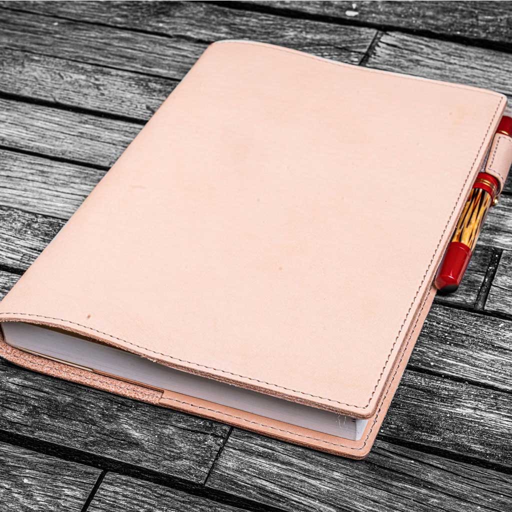 Natural undyed leather notebook cover with a pen on a wooden surface