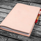Natural undyed leather notebook cover with a pen on a wooden surface