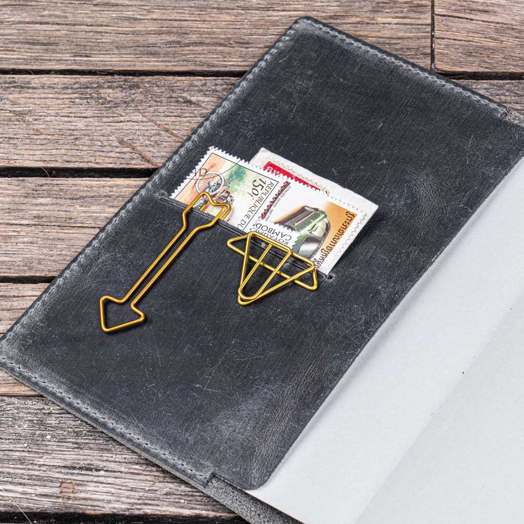Gray notebook cover with gold paper clips and stamps