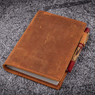 Brown leather notebook with red pen on a gray textured background