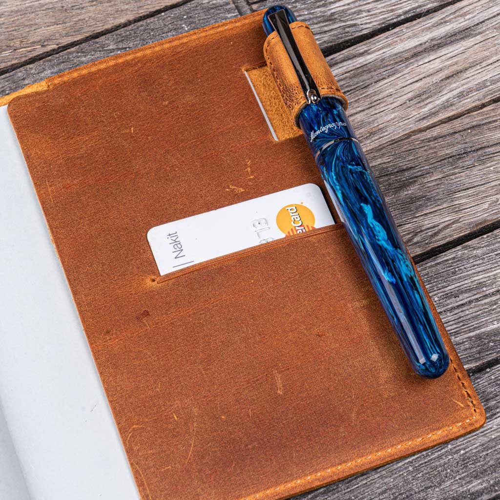 Brown leather notebook with a blue pen on a wooden surface
