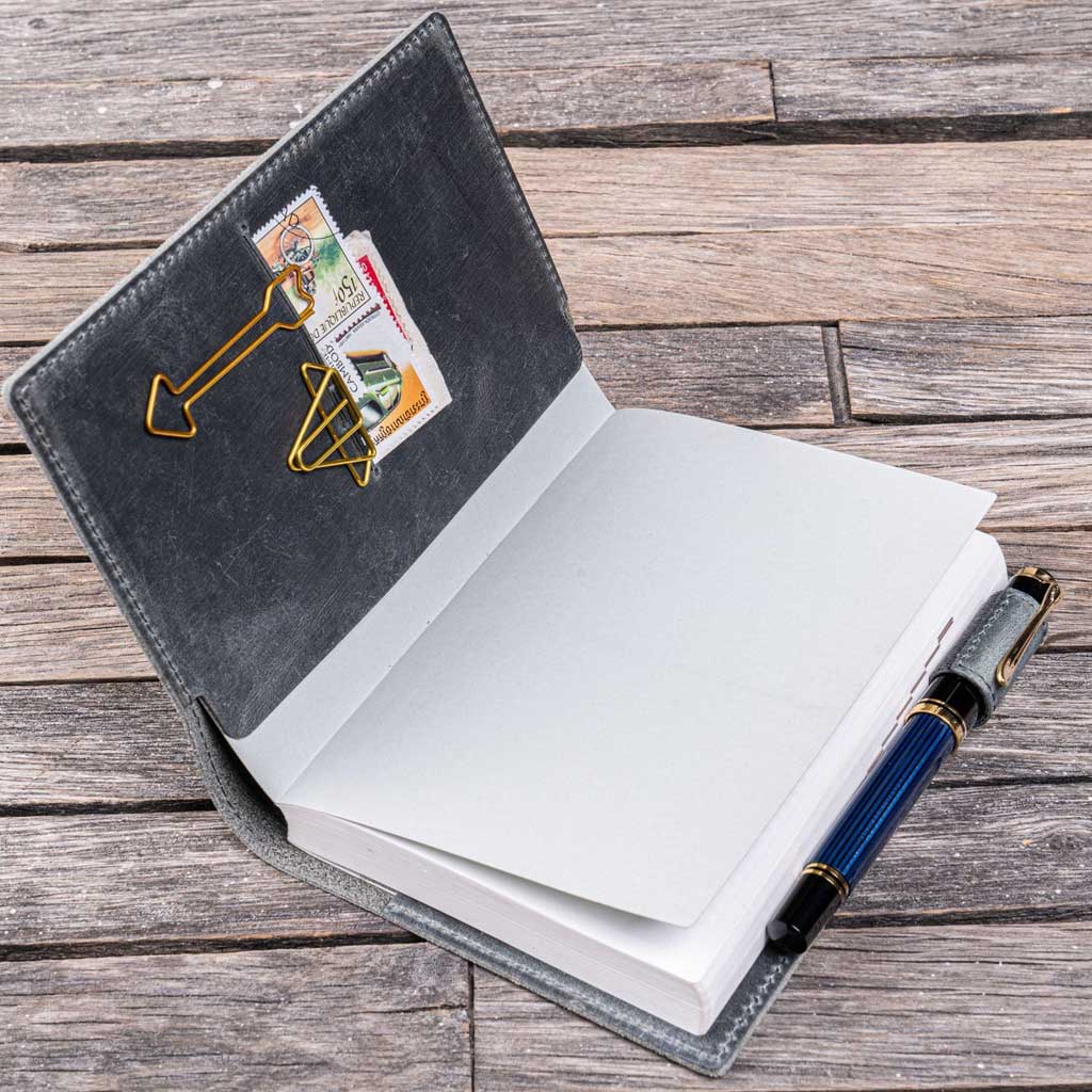 Open gray notebook cover with a pen on a wooden surface