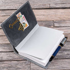 Open gray notebook cover with a pen on a wooden surface
