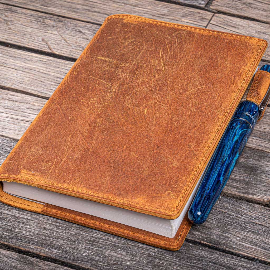 Brown leather notebook with a blue pen on a wooden surface