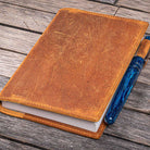 Brown leather notebook with a blue pen on a wooden surface