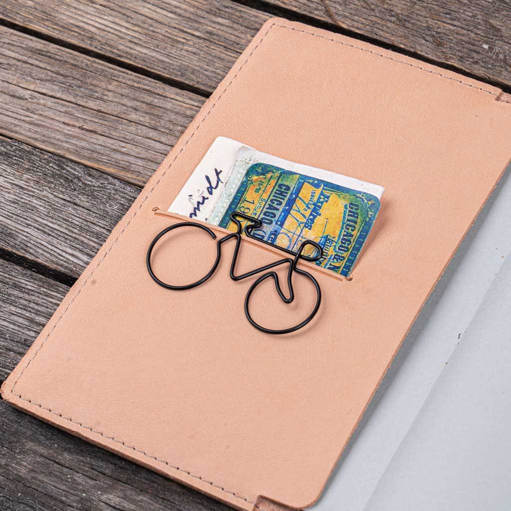 Natural undyed leather notebook cover with paper clip on wooden surface