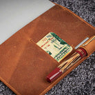 Brown leather wallet with pen on a textured surface