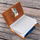 Open notebook with brown leather cover and pen and accessories on wooden surface