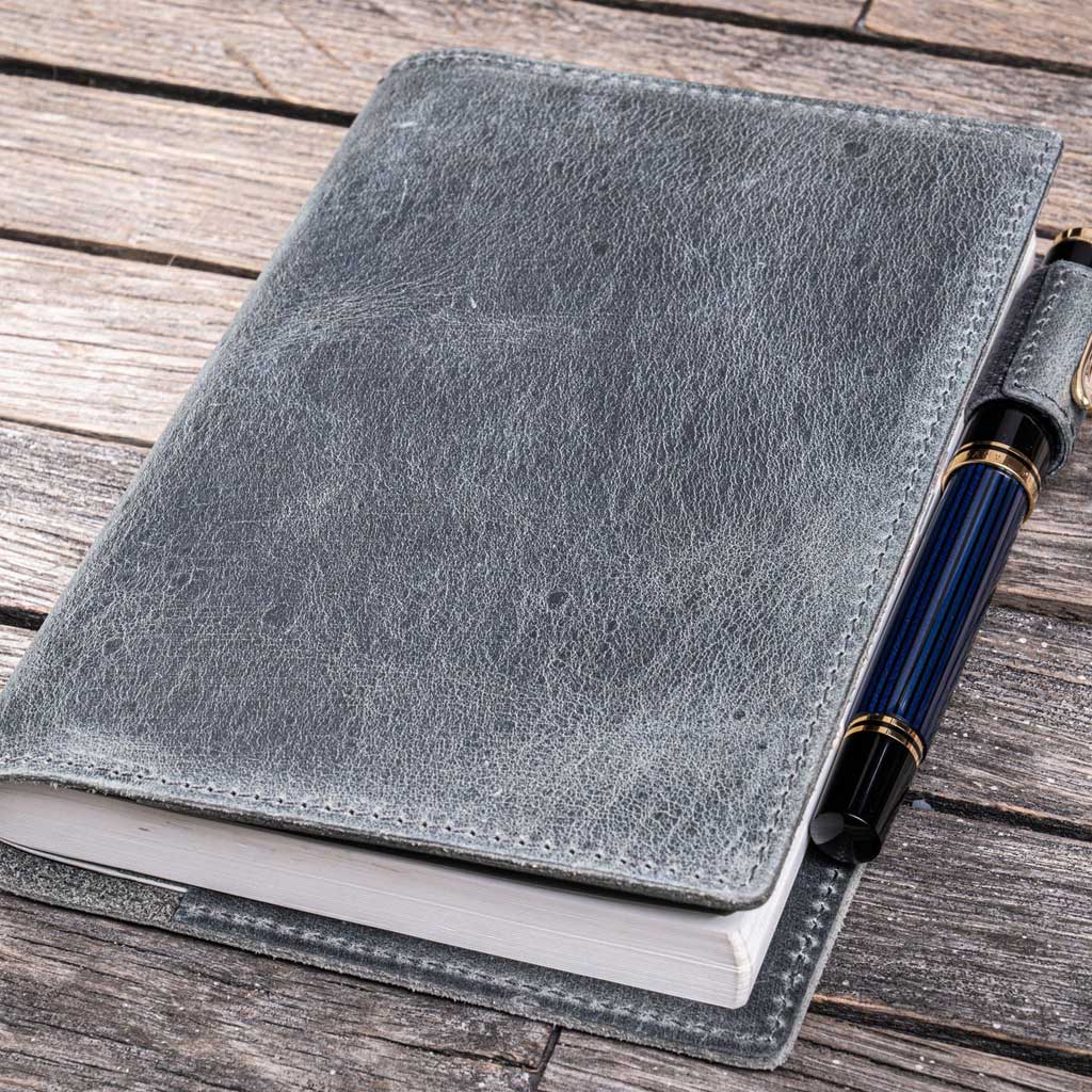 Gray leather notebook cover with a pen on a wooden surface