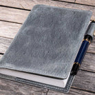 Gray leather notebook cover with a pen on a wooden surface