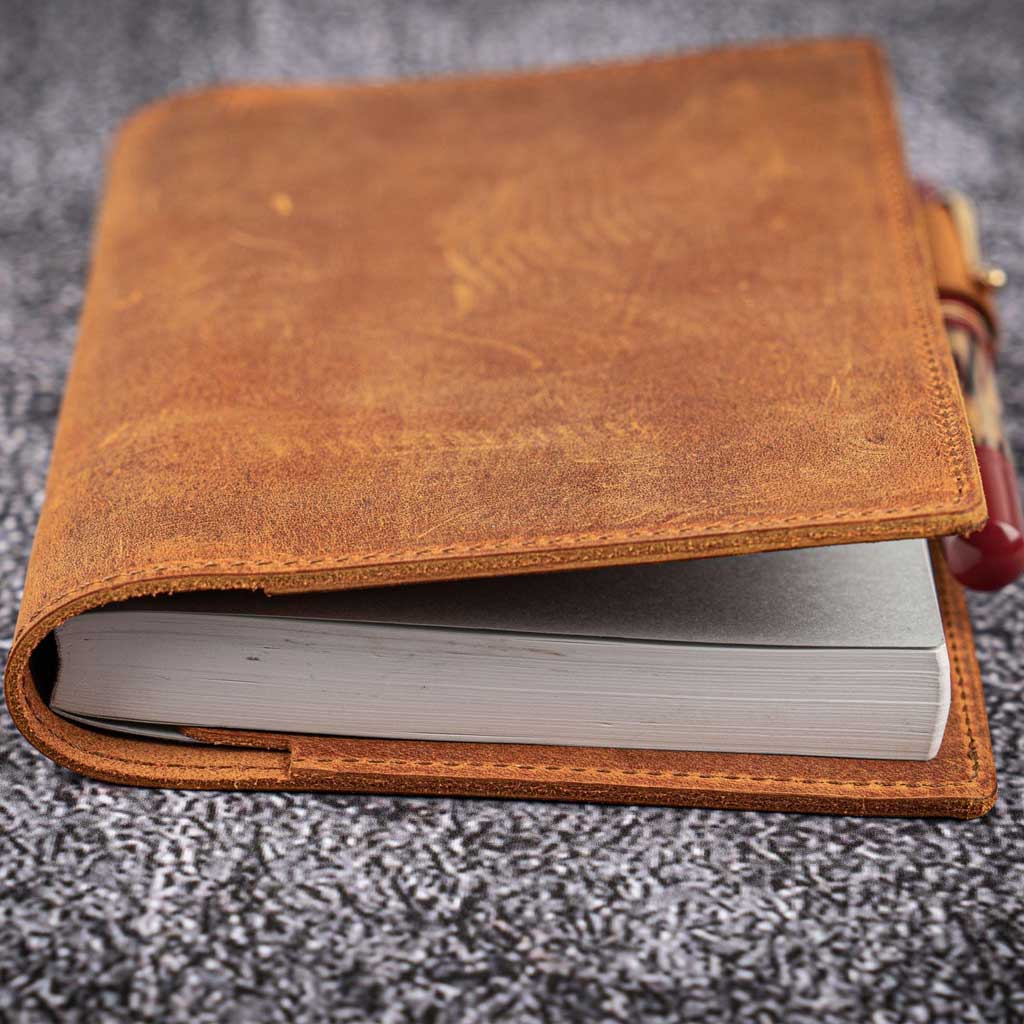 Brown leather notebook cover on a textured gray surface
