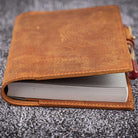 Brown leather notebook cover on a textured gray surface