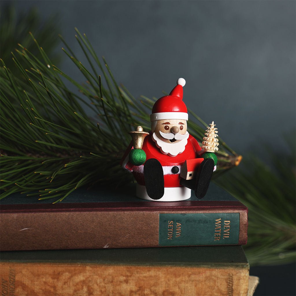 Small Santa Claus figurine sitting on a stack of books with a blurred green background
