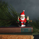 Small Santa Claus figurine sitting on a stack of books with a blurred green background